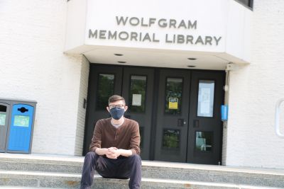 Student in mask sits in front of Wolfgram Memorial Library