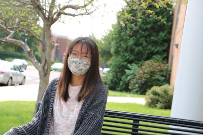 Student wearing mask sits on campus