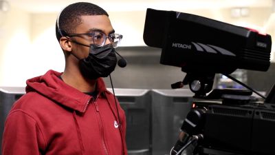 Andrew Proctor, wearing a mask and headset, filming in the studio