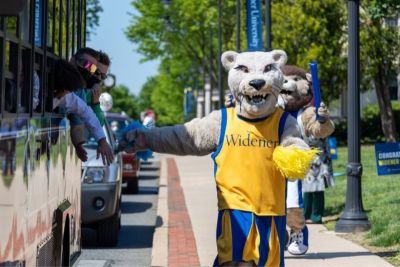 Widener lion mascot gives high fives to people in a trolley