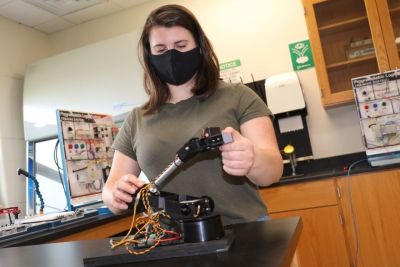Emily Wolfe works with a robotic mechanism in the lab