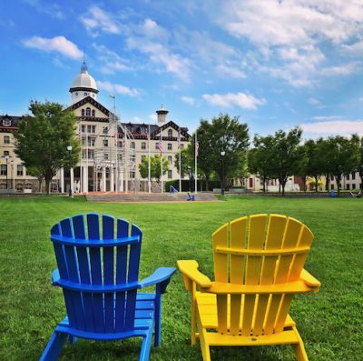blue and yellow chair sit on memorial field facing Old Main building