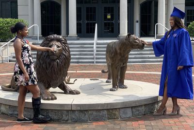 Sisters Arianna and Arielle McRae face each other while touching the noses of the Pride statues