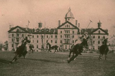 Old photo of students playing polo on Memorial Field with Old Main in the background