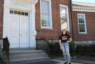 Chloe Mingioni stands outside of Muller Hall, which says "Admissions" over the door