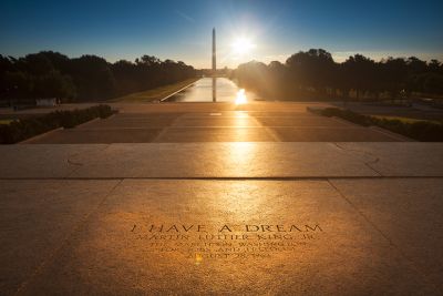 March on Washington Memorial with "I have a dream" inscribed in the cement and the Washington Monument in the background as the sun sets