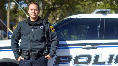Close up of a police officer leaning against police car. 