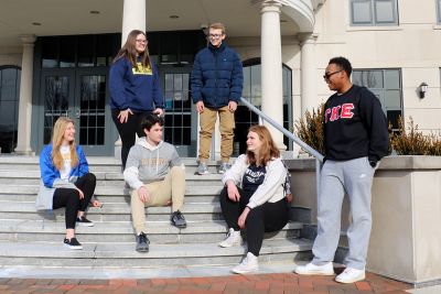 Six students on the steps of Founders Hall talking and laughing