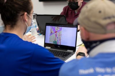 Civil engineering teammates review a color-coded map of Philadelphia on a computer screen. 