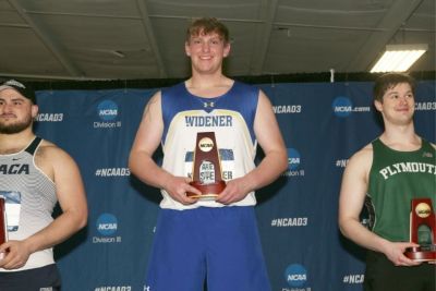 Widener athlete Alex Kristeller on the podium holding his NCAA trophy