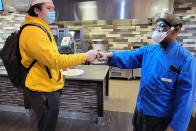 Student and employee John Shamburger fist bumping in the Pride cafe