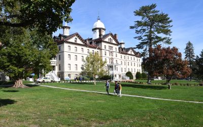 Group of students talking past Widener's historic Old Main building during a clear fall day