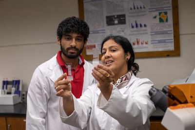 A professor and student examine a tissue sample in the lab.