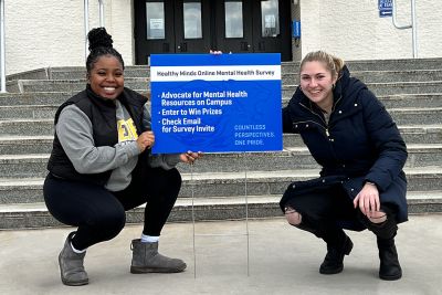 Two students pose with a law sign about a mental health survey