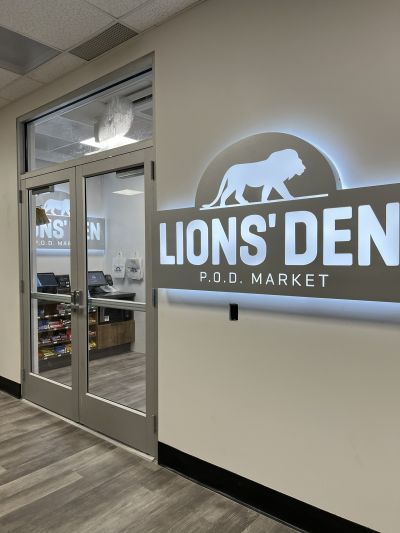 Lions' Den P.O.D. Market sign with a lion 