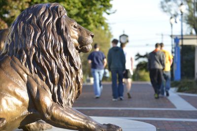 Lion statue to the left of the screen with out of focus people walking away
