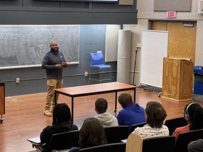 Kevin Brown speaks to student sin front of a chalk board