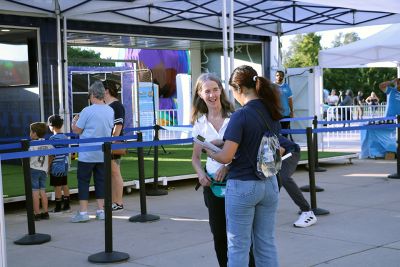 A student talks with a fan about the survey, there is a tent and soccer themed activity in the background