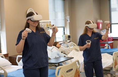 Female nursing students wear oculus headsets to practice in virtual simulated clinical settings.