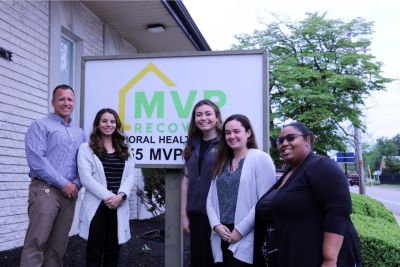 Staff members at MVP Recovery post outside in front of the business' sign