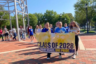 Students hold the Class of 2028 banner while walking under the dome.