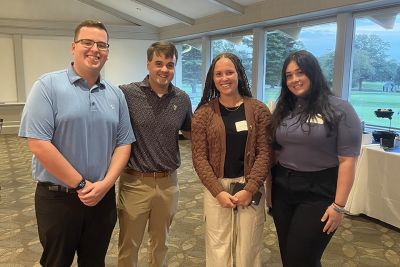 Four people stand and pose for a photo, smiling at the camera. 