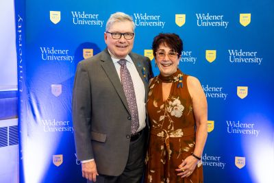 Michael and Marietta Borinski stand in front of a blue Widener University backdrop