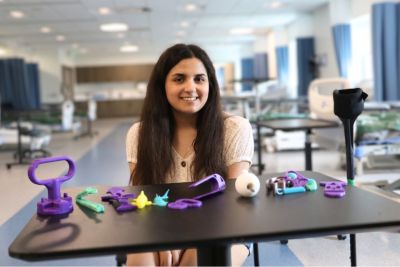 Lydia Aruffo ’25, a recent occupational therapy graduate, sits with a small selection of the 3D printed assistive devices she printed from open-sourced files and customized for clients as part of her capstone project. 