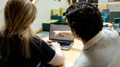 Two students in Widener University's MBA program look at a laptop while sitting in the on-campus Quick Center.