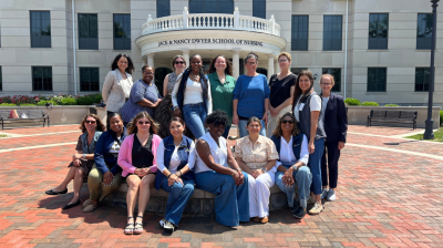 DON program first cohort seated in front of the Dwyer School of Nursing building