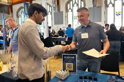 A student and employer exchange information at a career fair. 