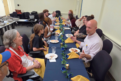 Group of students, faculty and staff sit around a table eating and talking