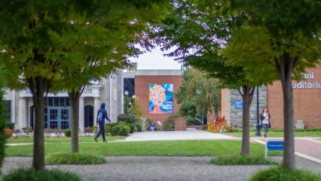 students walking campus in front of Kapelski Leadership Banner
