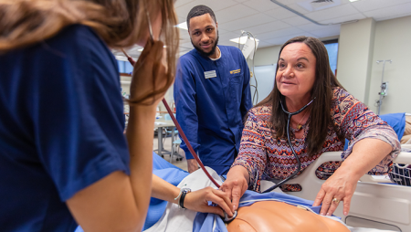 Two nursing students and one faculty member in a lab setting