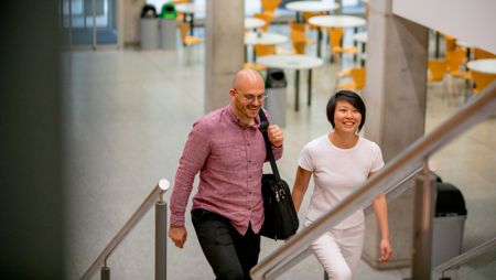 Two higher education administrators walking up stairs in academic building