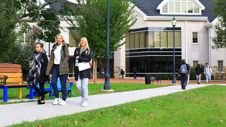 3 students walking in jackets in front of Widener's communications and computer science building