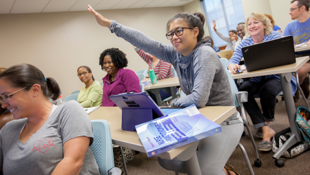 Nursing student excitedly raising hand in a classroom setting