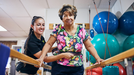 Physical therapy student working with client on parallel bars in Chester Community Clinic