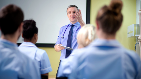 Professor in shirt and tie in front of classroom lecturing