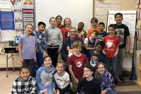 Superintendent Joseph Meloche sits in a classroom with children
