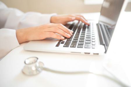 A health care professional sitting at a laptop preparing for a telehealth visit