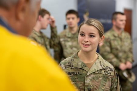R-O-T-C Cadet Meghan Rampolla speaks to someone, with cadets standing behind her