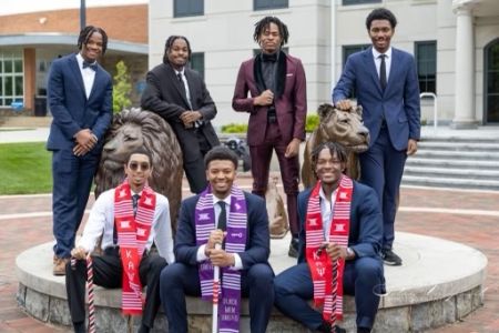 Seven members of Kappa Alpha Psi pose next to the Pride lion statues.