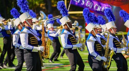 Five saxophone players in the Widener Marching Band performing on a football field
