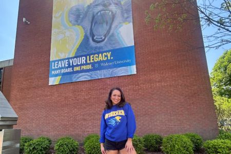 Belle Nicholas poses in front a mural on Widener's campus that reads "Leave Your Legacy."