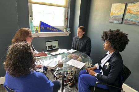 Three administrators and the (student) president for a day seated at a circular table in admissions.