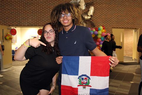 Two students in the University Center, with one holding a Dominican Republic flag