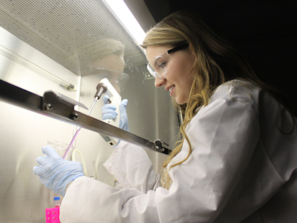Chemical engineering student in lab coat working under a hood