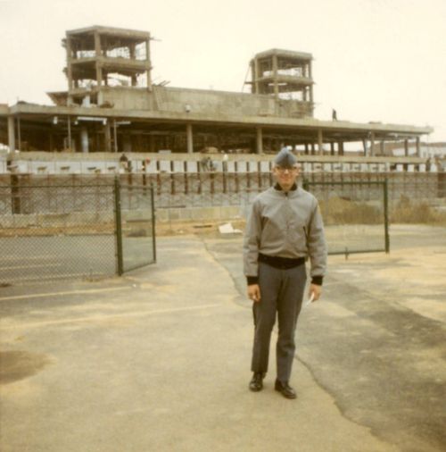 A cadet stands in front the construction site for the Wolfgram Memorial Library.