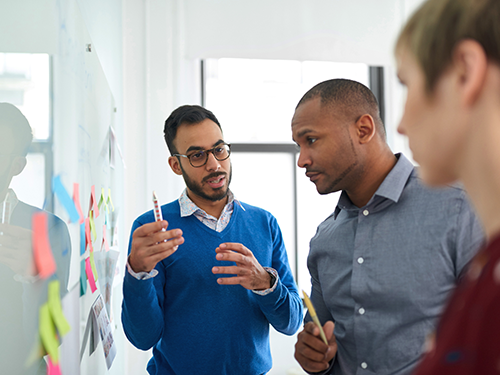 Three professionals solving a problem on a whiteboard